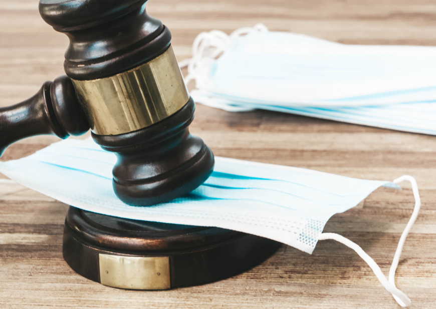 A judge's gavel hitting a COVID mask