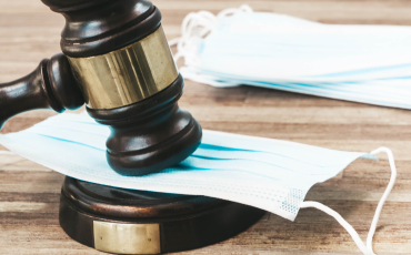 A judge's gavel hitting a COVID mask