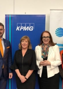 Six professionally dressed people stand in a row, smiling, in front of KPMG and Australian Human Rights Commission banners at an indoor event.